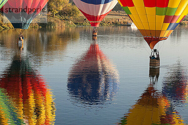 Mehrere Heißluftballons der Prosser Balloon Rally schweben auf dem Wasser des Yakima River; Yakima River  Prosser  Washington