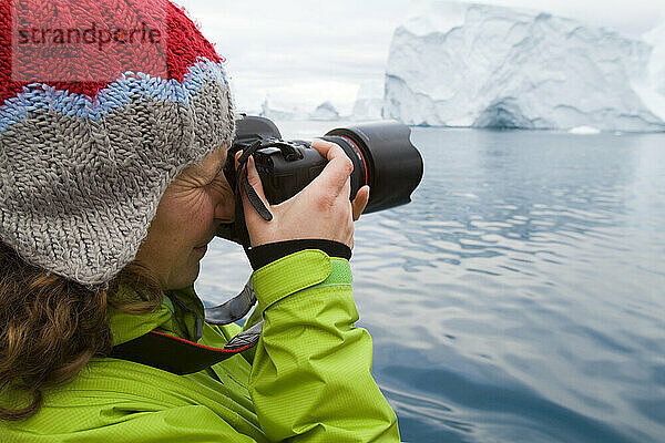 Frau auf mitternächtlicher Kreuzfahrt durch den Ilulissat-Eisfjord  eine Unesco-Welterbestätte. Grönland.