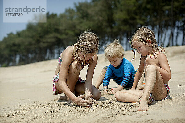 Kinder spielen im Urlaub zusammen und bauen Sandburgen  Turtle Beach  Goa  Indien.