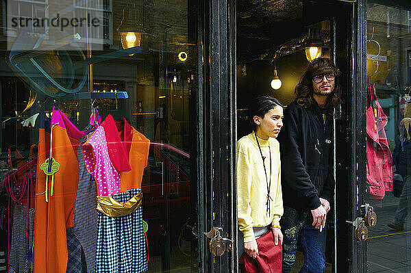 Ein junger Mann und eine junge Frau in der Tür eines Bekleidungsgeschäfts  Brick Lane; London  England