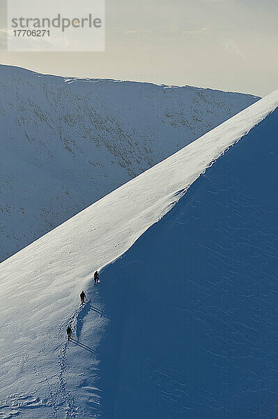 Wanderer erklimmen den verschneiten Bergrücken des Sgorr Dhearg im Winter in der Nähe von Glen Coe; Highlands  Schottland