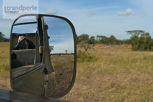 Blick in den Außenspiegel eines Geländewagens auf einen Touristen  der Wildtiere beobachtet  Ol Pejeta Conservancy; Kenia