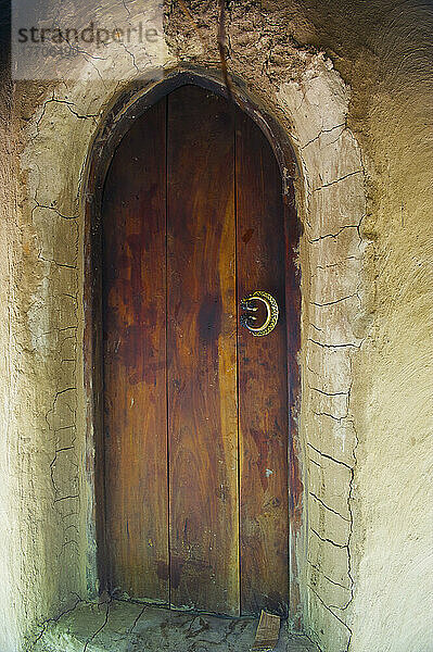 Eine gewölbte Holztür mit Rissen in der Wand; Ulpotha  Embogama  Sri Lanka