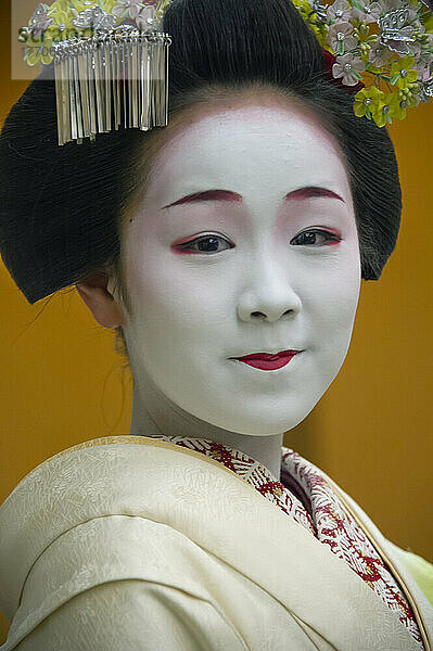 Porträt einer Maiko  einer Geisha-Lehrling in Kyoto und Westjapan. Ihre Arbeit besteht darin  bei Banketten und Festen für die Gäste Lieder und Tänze aufzuführen und auf dem Shamisen oder anderen traditionellen japanischen Instrumenten zu spielen. Maiko sind in der Regel zwischen 17 und 20 Jahre alt und erlangen nach einer gewissen Ausbildungszeit den Status einer Geisha. Diese Ausbildung dauert in der Regel einige Monate bis zu einem Jahr oder zwei Jahren  wobei Lehrlinge  die zu alt sind  um sich als Maiko zu kleiden  trotz ihrer Ausbildung die Stufe der Geisha überspringen können; Kyoto  Japan