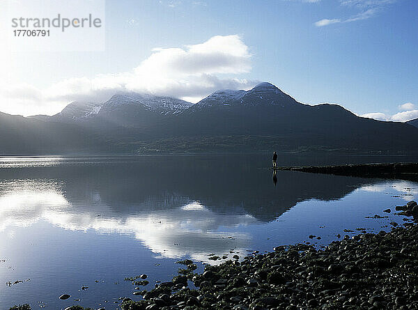 Mann steht am Ende eines Piers am Loch Torridon an einem ruhigen Morgen  Ross-Shire  Schottland.