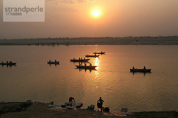 Boote auf dem Ganges und gewaschene Kleidung bei Sonnenaufgang. Die Kultur von Varanasi ist eng mit dem Ganges und der religiösen Bedeutung des Flusses verbunden: Sie ist die religiöse Hauptstadt Indiens und ein wichtiges Pilgerziel.
