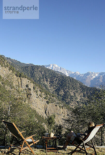 Ein Tourist sitzt mit Blick auf das indische Himalaya-Gebirge; Uttaranchal  Indien