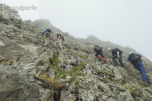 Wanderer beim Aufstieg zu einem steilen Felsen in der Nähe des Gipfels von Sgurr Alasdair in den Black Cuillin; Isle of Skye  Schottland