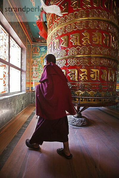 Ein Mönch dreht die größte Gebetsmühle der Welt in der Nähe der Boudhanath Stupa.