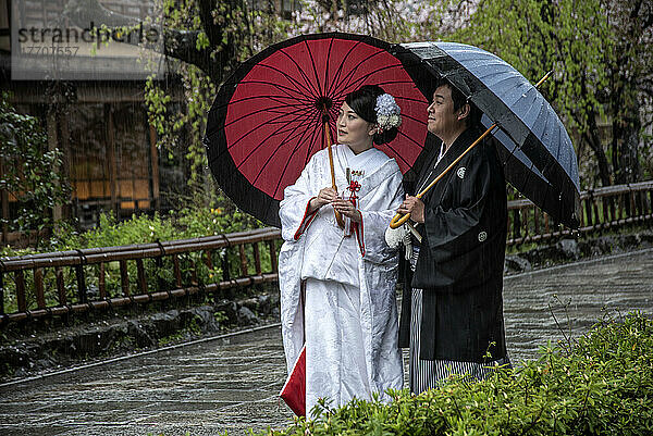 Paar in der Altstadt von Kyoto in traditioneller Kleidung bei einem Abendspaziergang im Regen; Kyoto  Japan
