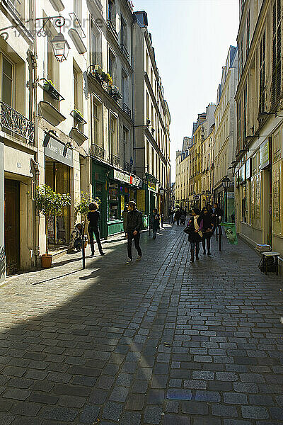 Fußgänger auf einem Gehweg zwischen Gebäuden im historischen Viertel Marais; Paris  Frankreich
