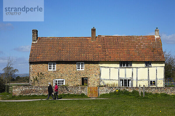 Ein Paar spaziert an einem Haus mit zwei verschiedenen Fassaden vorbei; Frampton Upon Severn  Gloucestershire  England