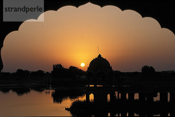 Blick auf den Gadi Sagar Tank durch einen Torbogen bei Sonnenaufgang; Jaisalmer  Rajasthan  Indien