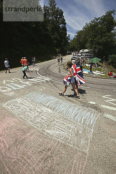 Britische Fans passieren niederländische Flaggen  bevor die Radfahrer den steilen Berg zum Plateau De Beille hinauffahren  Tour De France; Pyrenäen  Frankreich