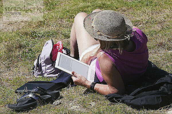 Touristin beim Entspannen und Lesen eines Buches auf ihrem Tablet oberhalb des Chamonix-Mont-Blanc-Tals; Frankreich