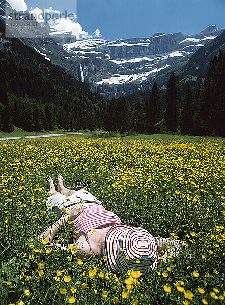 Frau entspannt im Feld der Butterblumen mit dem Cirque De Gavarnie im Hintergrund