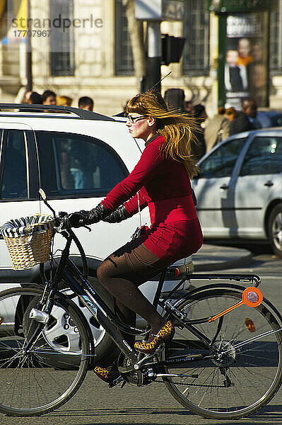 Eine Frau in formeller Geschäftskleidung fährt mit dem Fahrrad im Verkehr; Paris  Frankreich