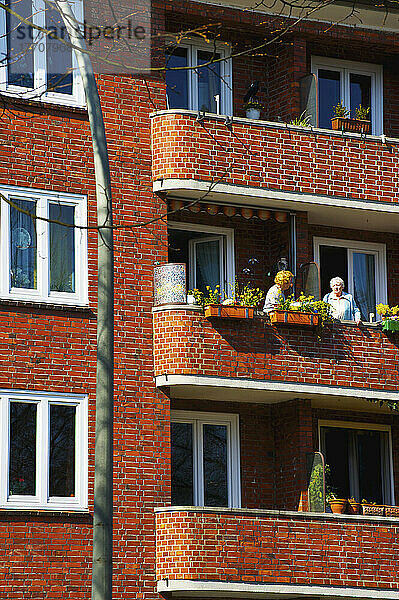 Freunde genießen den Balkon in einem Backsteinbau; Hamburg  Deutschland