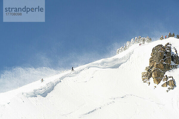 Skifahrer und Snowboarder wandern auf einem windigen Bergrücken oberhalb des Skigebiets Squaw Valley  Truckee  Squaw Valley  CA  USA; Truckee  Kalifornien  Vereinigte Staaten von Amerika