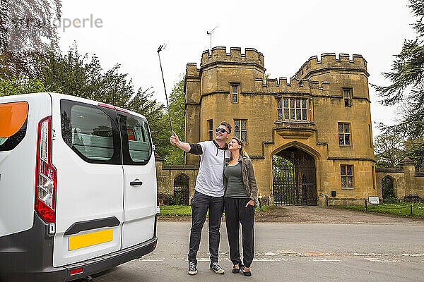 Ein Paar in einem Wohnmobil hält für ein Selfie vor dem Schloss Sudeley an; Winchcombe  England  UK