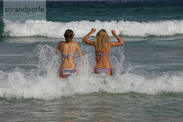 Mädchen in passenden Bikinis gehen ins Meer.