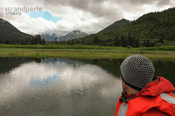 Ein Mann blickt auf die Berge  die Landschaft und das Wasser vor ihm; Inside Passage  Alaska