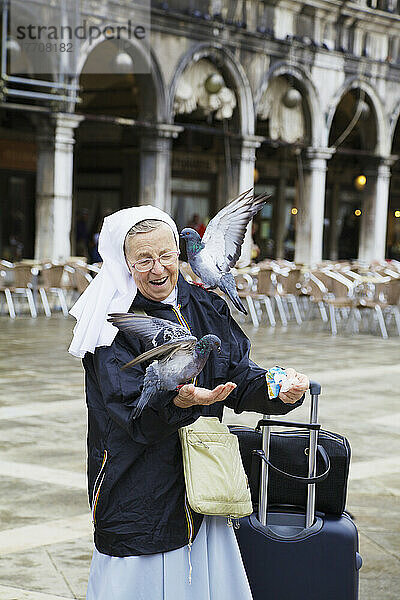 Nonne füttert Tauben auf dem Markusplatz; Venedig  Venetien  Italien