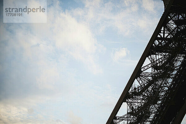 Besucher erklimmen eines der Beine des Eiffelturms in Paris  während die Sonne über der Stadt untergeht; Paris  Frankreich