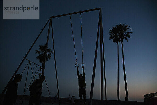 Silhouette von Menschen spielen auf Spielplatz Ausrüstung am Strand bei Sonnenuntergang; Kalifornien  Vereinigte Staaten von Amerika