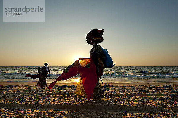 Silhouette einer Frau  die am Strand in der Abenddämmerung indische Tücher verkauft; Candolim  Goa  Indien