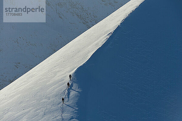 Wanderer klettern auf dem verschneiten Bergrücken von Sgorr Dhearg im Winter in der Nähe von Glen Coe; Highlands  Schottland