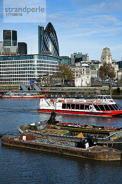 Das Gherkin-Gebäude dominiert die Skyline mit Touristenbooten und Schrottkähnen auf der Themse; London  England