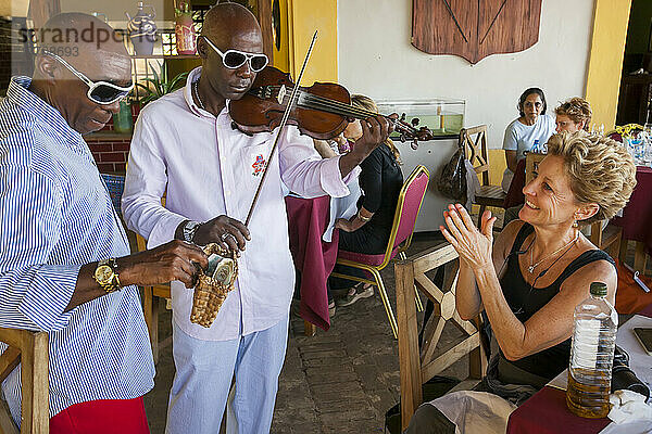 Ein Tourist in einem Restaurant in Havanna  Kuba  applaudiert zu einer Geigenmusik  während ein Mann Geld für die Unterhaltung sammelt; Havanna  Kuba