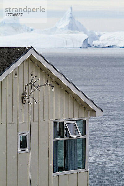 Die Jagd ist ein wichtiger Bestandteil des Lebens in Grönland  und Felle und Geweihe kann man überall in der Stadt sehen. Haus mit Eisfjord dahinter. Ilulissat  Grönland.