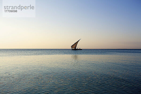 Ein Segelboot in der Ferne auf dem ruhigen Wasser des Indischen Ozeans; Vamizi Island  Mosambik