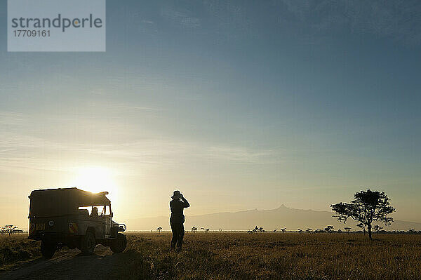 Silhouette einer Frau  die durch ein Fernglas vor dem Berg Kenia in der Morgendämmerung schaut  Ol Pejeta Conservancy; Kenia