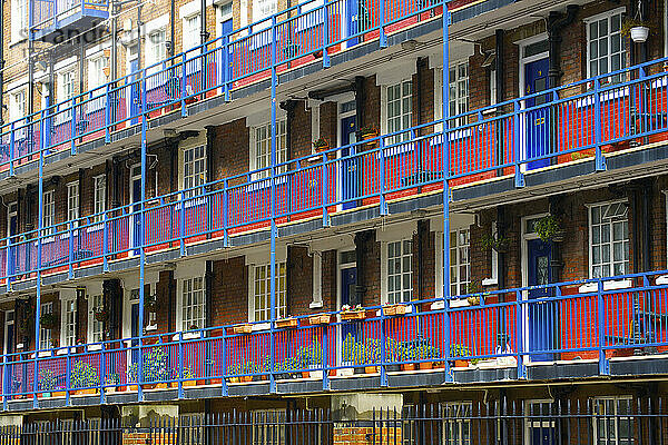 Backsteingebäude mit blauen Geländern und Türen auf den Balkonen und einem rot gestrichenen Streifen in der unteren Hälfte der Wände; London  England