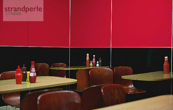 Sitzgelegenheiten in einem Restaurant mit einer halb schwarzen und halb leuchtend roten Wand; London  England