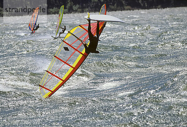 Dramatischer Blick auf einen Windsurfer  der kopfüber auf seinem Brett steht  während sich das Surfbrett und das Segel auf dem Wasser des Columbia River in der Nähe von Hood River in Oregon  USA  drehen; Oregon  Vereinigte Staaten von Amerika