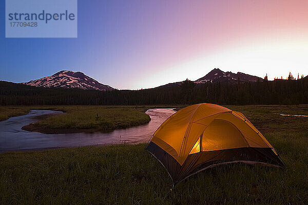 Glühend helles Zelt am Ufer eines großen Sees bei Sonnenaufgang mit dem Mount Washington im Hintergrund; Oregon  Vereinigte Staaten von Amerika