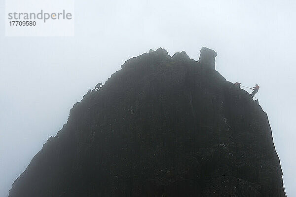 Menschen  die den unzugänglichen Gipfel auf der linken Seite erklimmen  während andere sich auf der rechten Seite bei nebligen Bedingungen abseilen  Sgurr Dearg; Isle Of Skye  Schottland