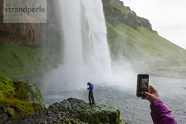 Eine Frau fotografiert den Wasserfall Seljalandsfoss; Seljalandsfoss  Island