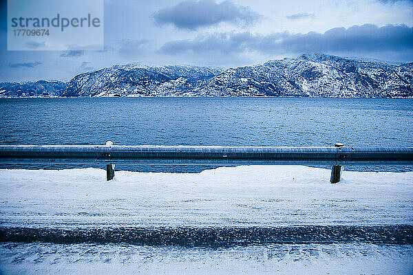 Tückische  eisige Straße  die sich um den Berghang und das Fjordufer windet  mit dramatischer Aussicht auf die Berge; Ortnevik  Sognefjord  Norwegen