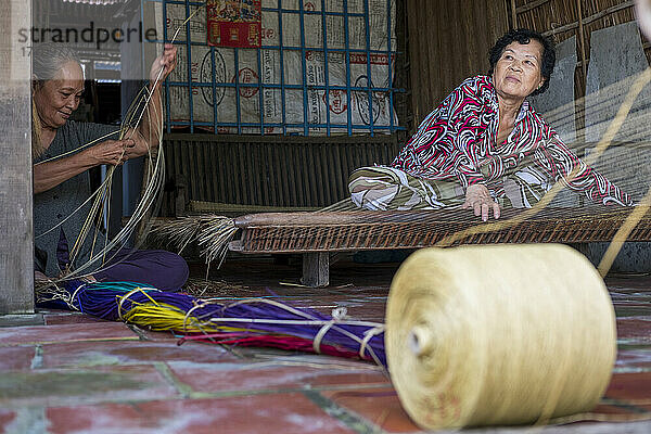 Zwei Frauen flechten gemeinsam eine Rattanmatte in Vietnam; Binh Thanh Island  Vietnam
