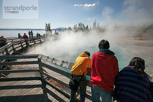 Touristen lehnen sich über ein Geländer  um die geothermischen Eigenschaften eines Geysirbeckens zu beobachten; Yellowstone National Park  Wyoming