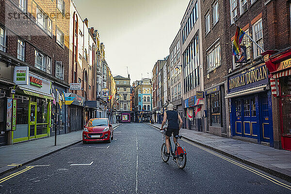 Mann auf dem Fahrrad auf einer leeren Straße in Soho zur abendlichen Hauptverkehrszeit während der nationalen Abriegelung wegen der Covid-19-Pandemie; London  England  UK