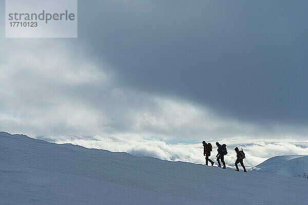 Drei Wanderer auf einem verschneiten Winterspaziergang beim Aufstieg zum Geal Charn  in der Nähe von Laggan; Schottland