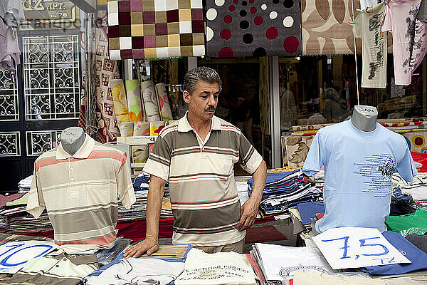 Standinhaber  der Herrenhemden verkauft  zwischen zwei Attrappen auf dem Carsamba Pazari  dem Mittwochsmarkt in Fatih  einem der ältesten und farbenprächtigsten Märkte Istanbuls  der sich in einem Netz von Straßen rund um die Fatih-Moschee in Istanbul  Türkei  befindet. Foto