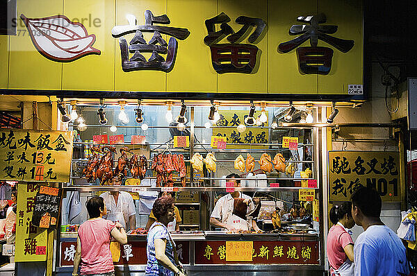 Menschen zu Fuß durch Street Food Stand  Fleisch und Geflügel in der Mong Kok Markt  Kowloon. Hongkong; Kowloon  Hongkong.