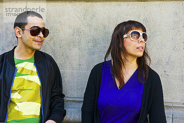 Ein Mann und eine Frau mit Sonnenbrille  die an einer Betonwand stehen; Barcelona  Spanien